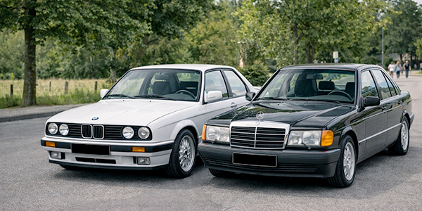 BMW E30 und Mercedes 190 W201 nebeneinander geparkt – zwei alltagstaugliche 80er-Jahre-Youngtimer, die sich als zuverlässige Gebrauchtwagen in Österreich eignen.