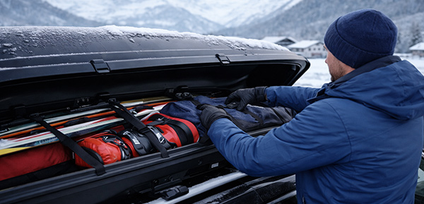 Dachbox wird mit Wintersportausrüstung sicher beladen.