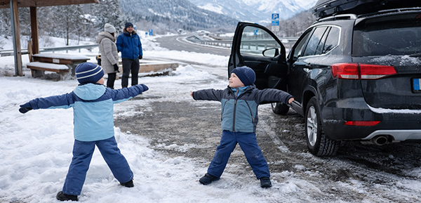 Familie macht Pause auf winterlicher Autofahrt mit Kindern in Österreich.