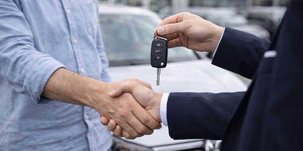 Händedruck und Schlüsselübergabe bei Abschluss des Gebrauchtwagenkaufs