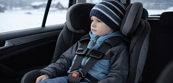 Kind sitzt korrekt gesichert in einem Kindersitz auf der Rückbank eines Autos.
